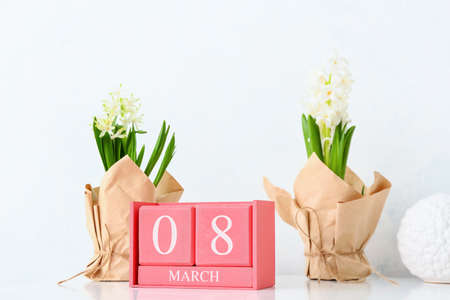 Cube calendar with date MARCH 8 and flowers on table. International Women's Day celebration