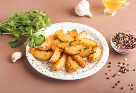 Plate of tasty fried potatoes with parsley on color backgroundの写真素材