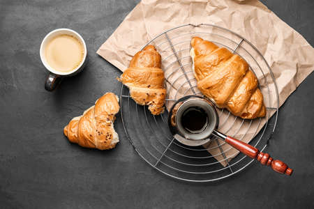 Pot, cup of coffee and croissant on dark backgroundの写真素材