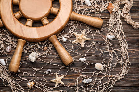 Helm, net and sea shells on wooden background