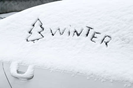 Word WINTER written on snow covered car windowの写真素材