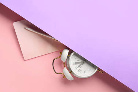 Alarm clock, notebook and pen on color backgroundの写真素材