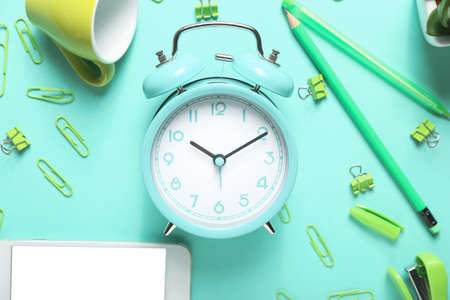 Composition with alarm clock, mobile phone and stationery on color background