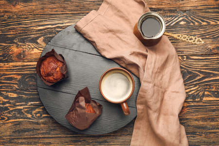 Pot, cup of freshly brewed coffee and muffins on wooden tableの写真素材