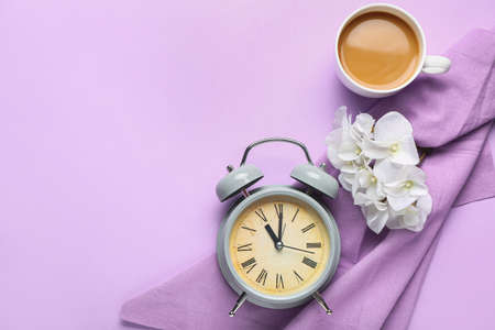 Composition with alarm clock and cup of coffee on color background