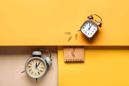 Alarm clocks and notebook on color backgroundの写真素材