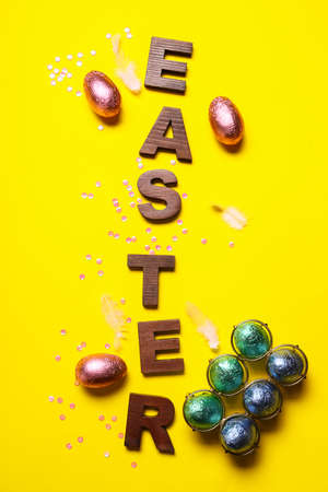 Word Easter and sweet chocolate eggs on color backgroundの写真素材