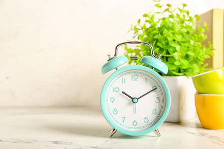 Alarm clock, cups and houseplant on light backgroundの写真素材