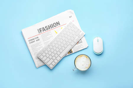 Cup of coffee, keyboard, PC mouse and newspaper on color background