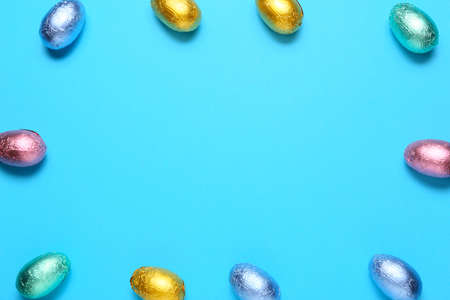 Frame made of sweet chocolate eggs on color background