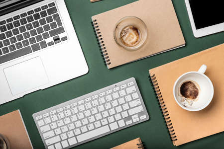 Composition with empty cups, notebooks and gadgets on color backgroundの写真素材