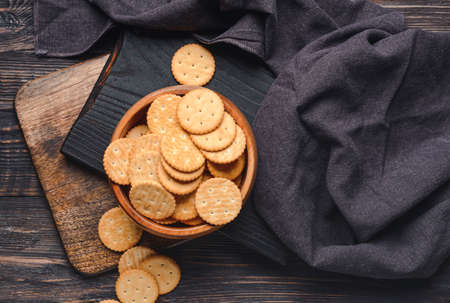 Bowl of tasty crackers on dark wooden backgroundの写真素材