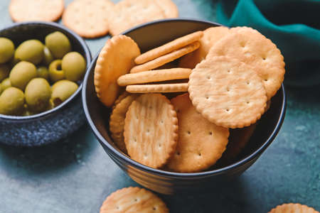 Bowl of crackers and olives on color backgroundの写真素材