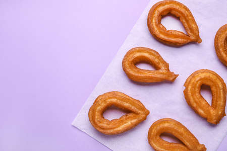 Parchment with tasty churros on color background