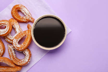 Parchment with tasty churros and melted chocolate sauce on color background, closeupの写真素材