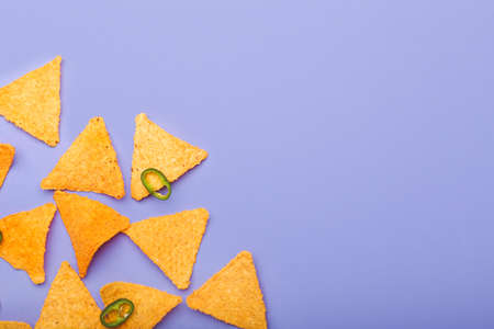 Tasty nachos with chili pepper on color background