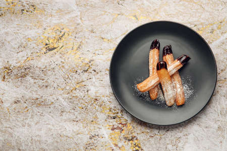 Plate with tasty churros dipped in chocolate on grunge backgroundの写真素材