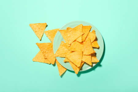 Plate with tasty nachos on color background