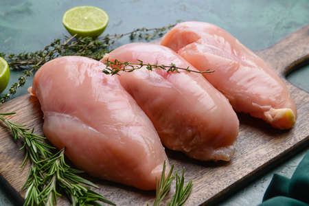 Board with raw chicken fillet on color background, closeupの写真素材