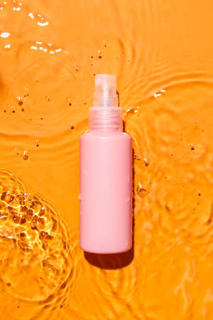 Bottle of cosmetic product in water on color backgroundの写真素材