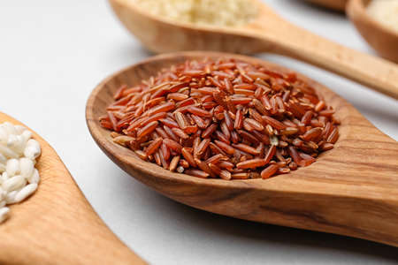 Spoons with different types of raw rice on light background, closeupの写真素材