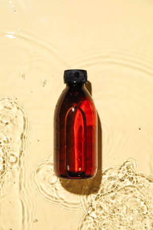 Bottle of cosmetic product in water on color backgroundの写真素材