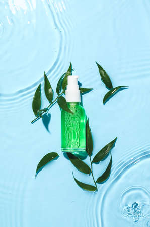 Bottle of cosmetic product and leaves in water on color backgroundの写真素材