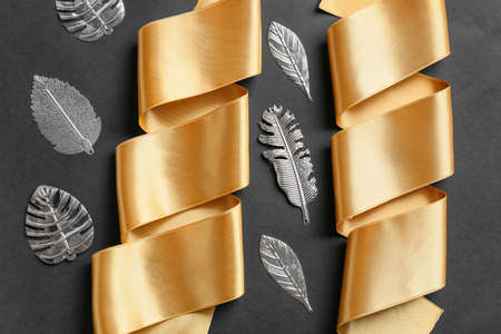 Composition with beautiful golden ribbons and leaves on dark backgroundの写真素材