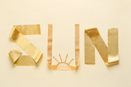Word SUN made of beautiful golden ribbons on color background