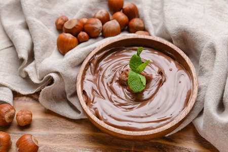 Bowl with tasty chocolate paste and hazelnuts on wooden backgroundの写真素材