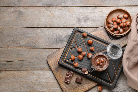 Jar with tasty chocolate paste and hazelnuts on wooden backgroundの写真素材