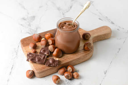 Jar with tasty chocolate paste and hazelnuts on light backgroundの写真素材