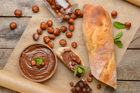 Bowl with tasty chocolate paste and hazelnuts on wooden backgroundの写真素材