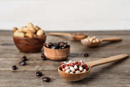 Bowls and spoons with different legumes on wooden background, closeupの写真素材