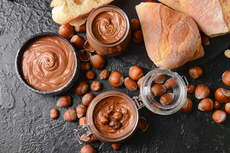 Composition with tasty chocolate paste and hazelnuts on dark backgroundの写真素材