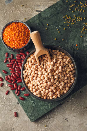 Bowls with different legumes on gray background