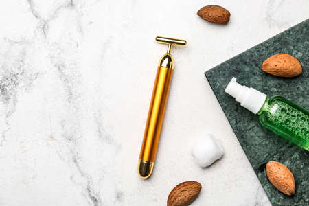 Composition with facial massage tool, cosmetic product and nuts on light backgroundの写真素材