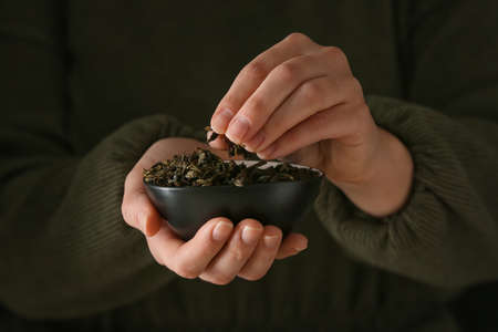 Woman holding bowl with dry green tea leaves, closeupの写真素材