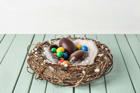 Nest with chocolate Easter eggs on wooden table