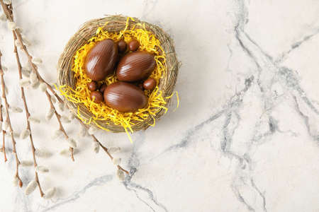 Nest with chocolate Easter eggs on light backgroundの写真素材