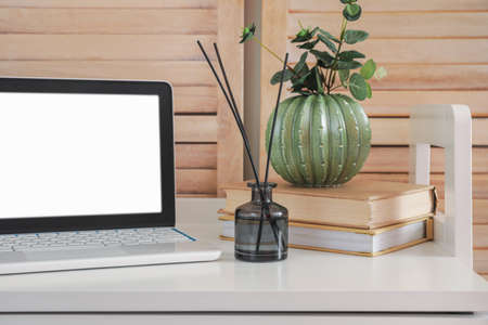 Reed diffuser and laptop on table in room