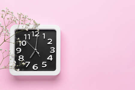 Stylish clock and beautiful flower on color backgroundの写真素材