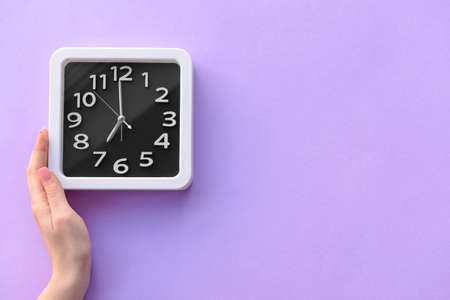 Female hand with stylish clock on color background, closeup