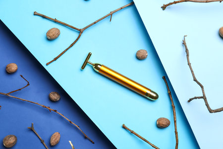 Facial massage tool with nuts and tree branches on color backgroundの写真素材