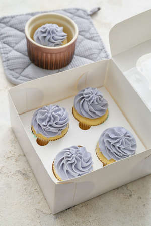 Box with tasty cupcakes on light background