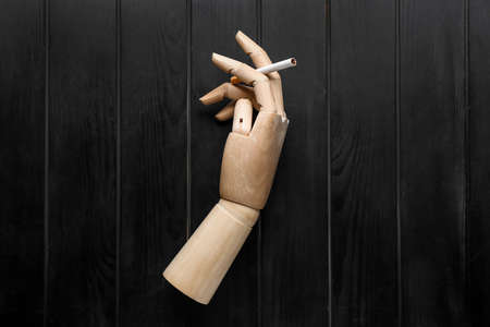 Wooden hand with cigarette on dark backgroundの写真素材