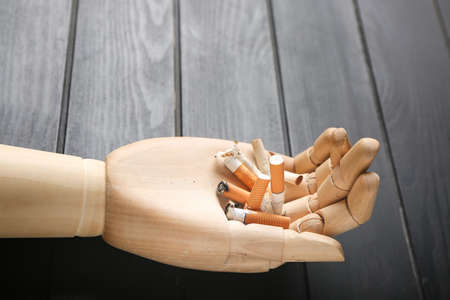 Wooden hand with cigarettes on dark background, closeupの写真素材