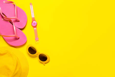 Stylish sunglasses, hat, wrist watch and flip-flops on color backgroundの写真素材
