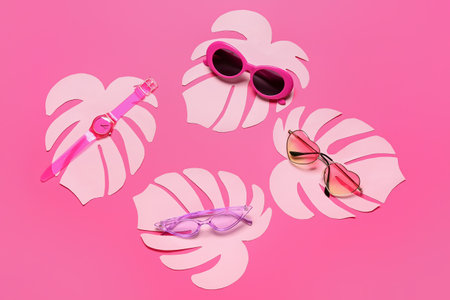 Composition with stylish sunglasses, wrist watch and paper palm leaves on color backgroundの写真素材