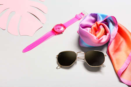 Stylish sunglasses, wrist watch and kerchief on gray background